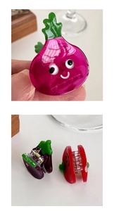 Detailed view of carrot-shaped acetate hair clips in pink, purple and green colors