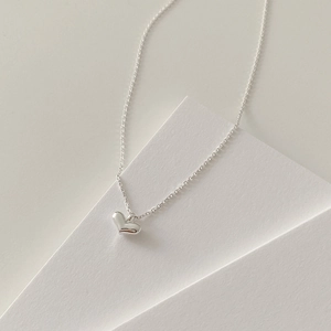 Detailed close-up of a minimalist 3D heart pendant necklace with high polished finish