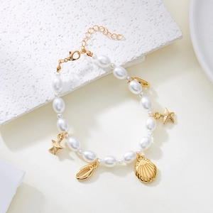 Bohemian gold starfish and shell pearl anklet for women on a stone background