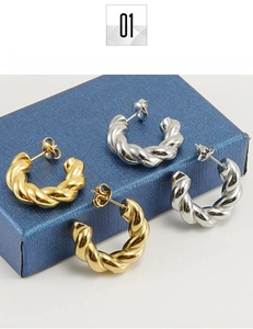 Macro detail of twisted gold and silver titanium steel earrings on a gift box