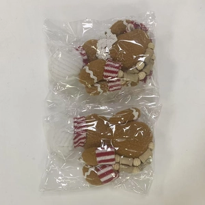 Detail of gingerbread plush ornaments with red knit scarves and wooden beads in packaging