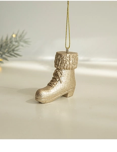 Detail of gold glitter Christmas boot ornament hanging above a minimalist surface