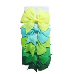 Detail of six gradient green ribbed ribbon fishtail bow hair clips on a display card