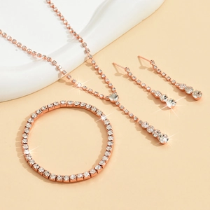Detailed view of rose gold necklace, bracelet and drop earrings set with white rhinestones