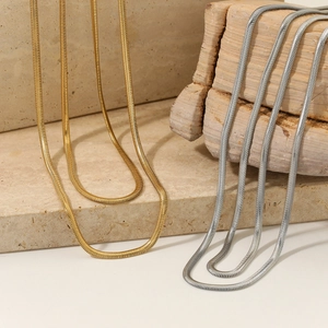 High-quality layered gold and silver snake chain necklaces on a stone pedestal
