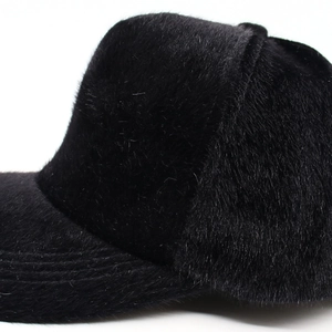 Close-up of black plush faux fur baseball cap showing dense texture and glossy finish