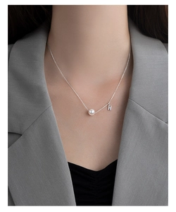Detail view of S925 silver necklace featuring a round white pearl and diamond letter H charm