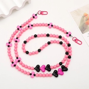 Detailed view of pink and black beaded crossbody phone chain with bow and heart charms