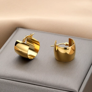 Polished golden wide C-shape geometric hoop earrings displayed on a premium jewelry box