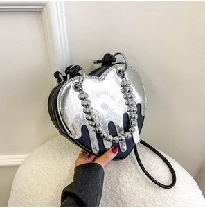 Macro detail of heart-shaped handbag with liquid silver drip and metal bead chain handle