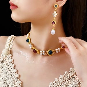 Close-up of vintage gold necklace and drop earrings with pearls and colorful gemstones