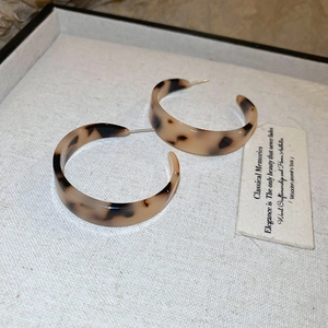 Macro shot of amber tortoise shell hoop earrings inside a premium gray jewelry box