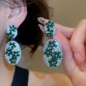 Detail view of oval flower earrings with green crystals and zircon on a model