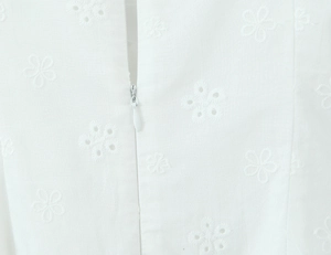 Detail of white cotton dress showing fine floral embroidery and a hidden zipper closure