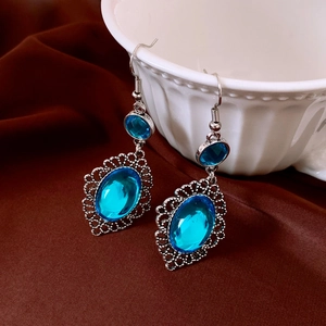 Dettaglio degli orecchini vintage in argento con pietre blu su una ciotola bianca