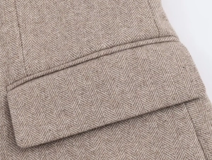 Detail shot of brown herringbone wool fabric and precise pocket stitching on the blazer