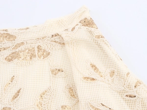 Detail of mesh lace fabric with elegant gold sequin embroidery on beige material