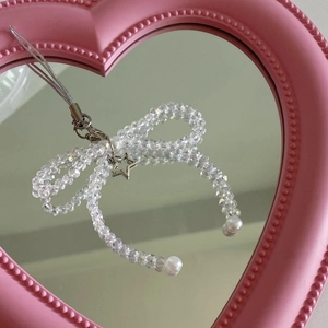 Detail of beaded bow phone charm with star pendant reflected in a pink heart-shaped mirror