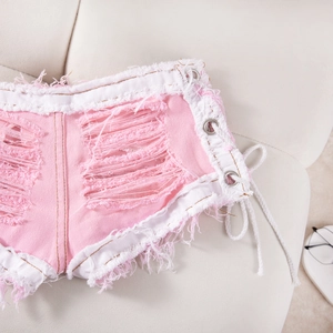 Detalle de los pantalones cortos vaqueros rosas y blancos con rotos y cordones laterales