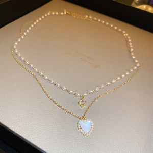 Detail of a vintage pearl and gold double-layered necklace with a heart-shaped opal pendant