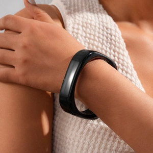 Close-up of a wide irregular black resin bangle with glossy finish on a woman's wrist