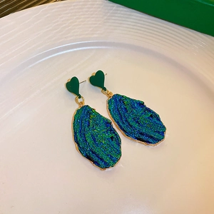 Macro detail of geometric heart earrings with blue textured resin and gold borders