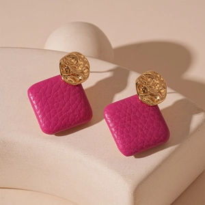 Detail of rose red square leather drop earrings with golden hammered metal studs