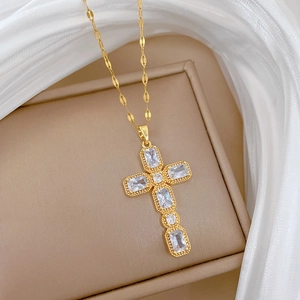 Vue détaillée d'un collier croix doré avec zircons rectangulaires sur de la soie