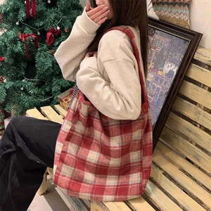 Close-up of red plaid tote bag made of thick wool fabric in a cozy Christmas setting