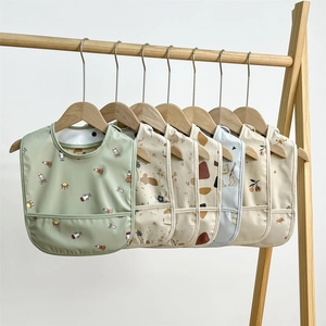 Waterproof baby bibs with cartoon patterns hanging on wooden hangers in various colors