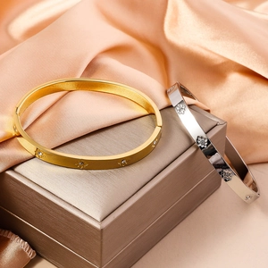 Close-up of gold and silver bangles with flower embossment and shiny zircons