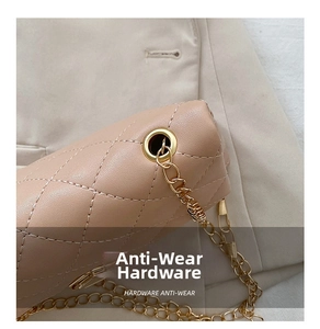 Close-up of quilted leather texture and gold metal chain strap on beige crossbody bag