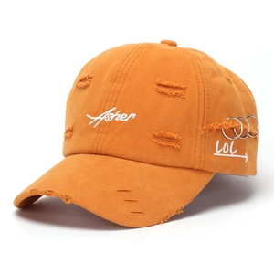 Close-up of mustard yellow baseball cap with distressed details and metal ring accents