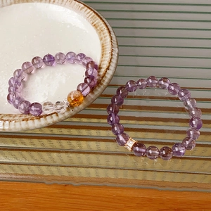 Macro shot of purple amethyst beaded bracelets with yellow crystal and gold zircon charm