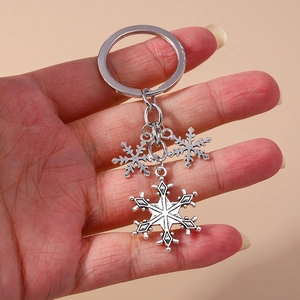 Detail showing silver alloy snowflake charms on a keychain held in hand for size view