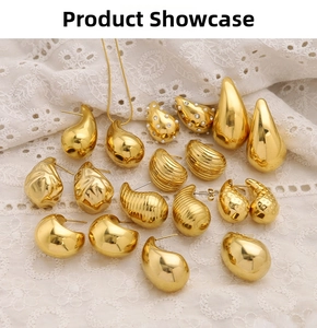 Detailed view of various 18K gold teardrop earrings and textured metal pendants on lace