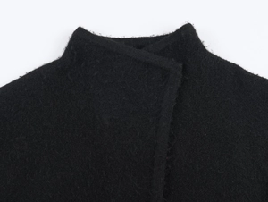Vue détaillée du col montant et du design superposé sur le manteau cape noir en laine