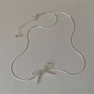 Close-up of S925 sterling silver bow pendant featuring delicate micro pearls and snake chain