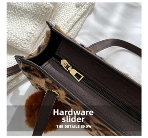 Detail of golden zipper on leopard print faux fur handbag with leather handle