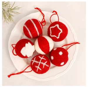 Detailed view of six red and white wool felt Christmas ornaments on a white ceramic plate