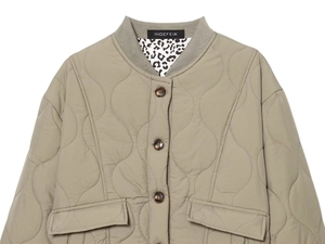 Detail of sage green quilted jacket with wave pattern and leopard print lining