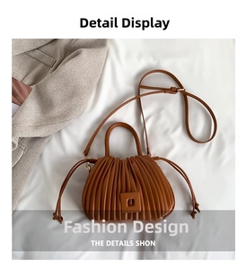 Detail of a brown pleated PU leather crossbody bag featuring a unique gathered texture