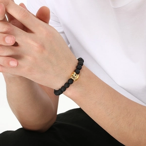 Lava rock bead bracelet with golden pig charm shown on a model's wrist for luck
