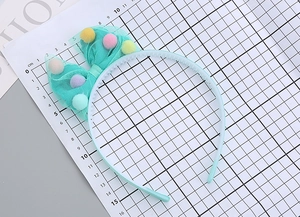 Detail of light blue mesh bow headband with colorful pompoms on a measuring mat