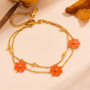 Detail of double-layer gold chain bracelet featuring three orange enamel flower pendants