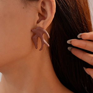 Gros plan d'une boucle d'oreille hirondelle abstraite taupe mat avec bordure dorée