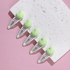 Close-up of five white metal BB clips with light green heart-shaped resin decorations