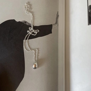 Polished silver teardrop pendant necklace on fashion magazine, minimalist chic style