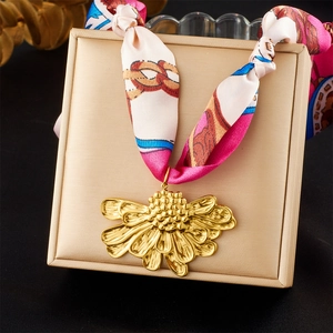 Détail d'un collier en ruban de soie avec pendentif fleur dorée sur un écrin