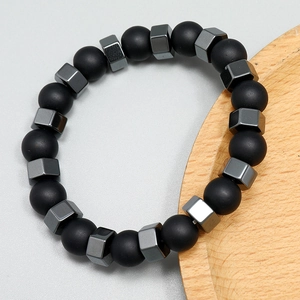 Detail of matte black beads and dark grey hexagonal metallic stones on stretch bracelet